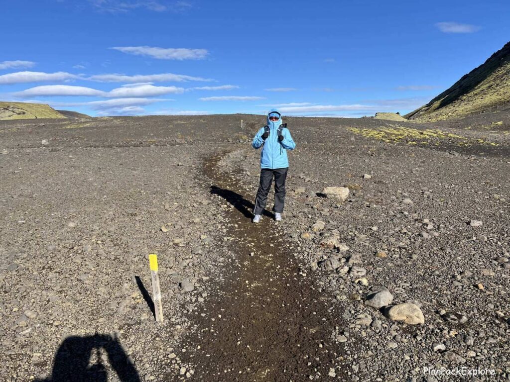 A person in a blue jacket on a gravel path to Mount Laki in Iceland.