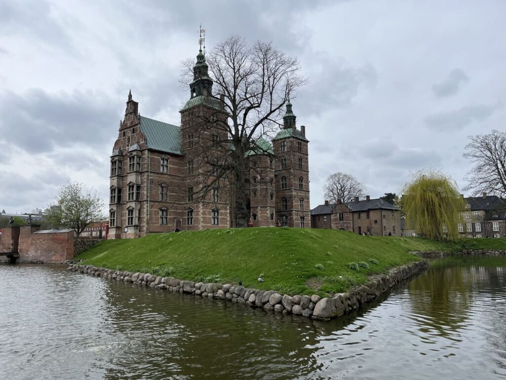 A palace surrounded by a green lawn and a moat in copenhagen.