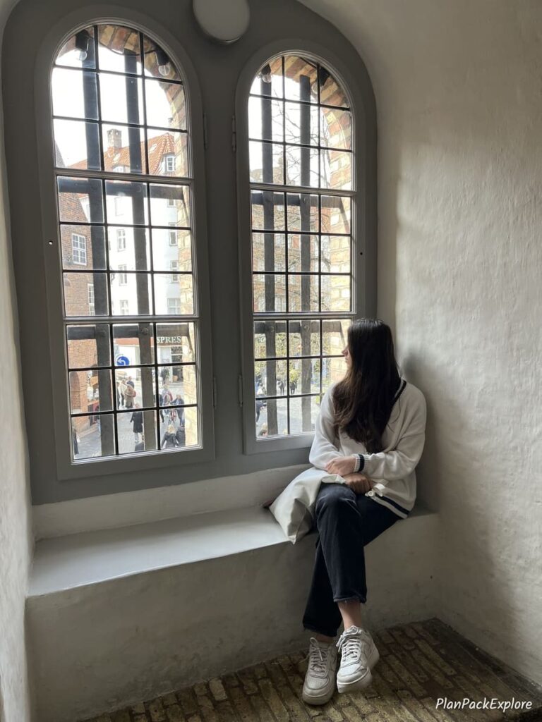 A person sitting in small nook with an arched window at the round tower in Copenhagen.