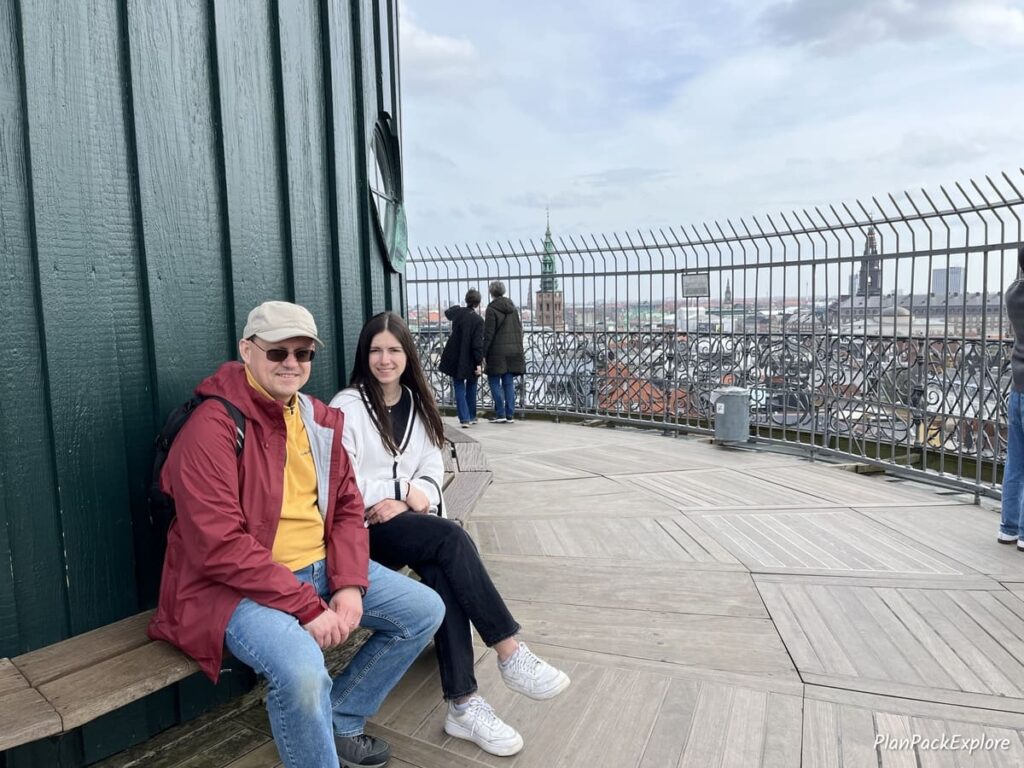 Two people sitting on a bench on the viewing platform at the Round Tower in Copenhagen.