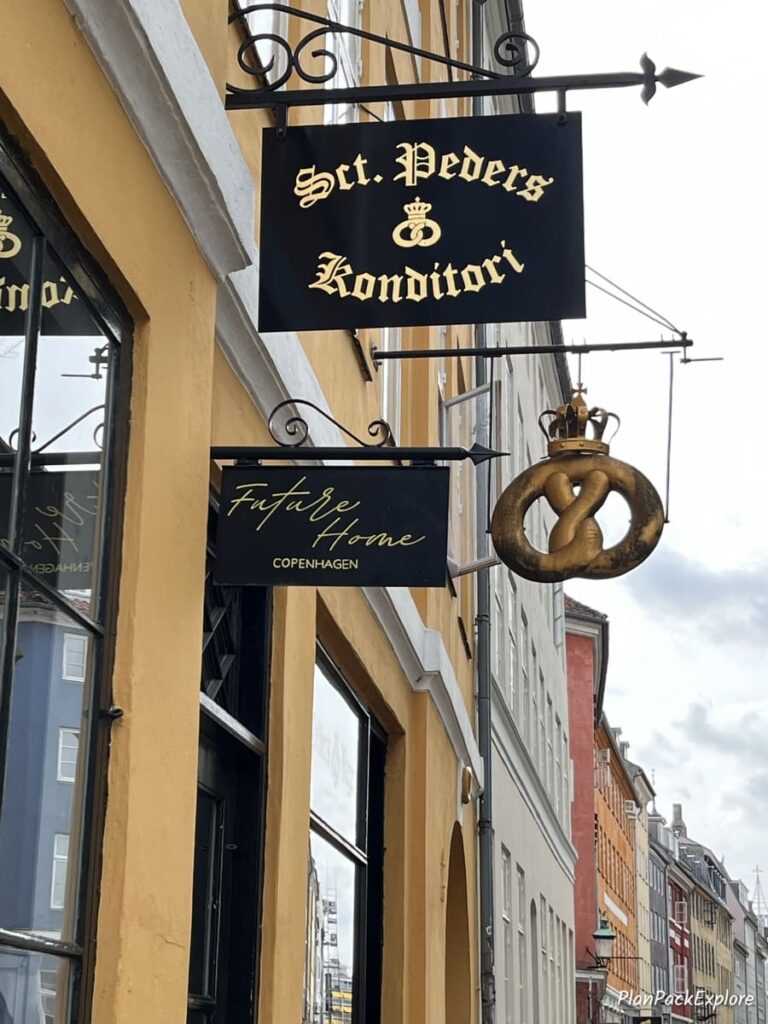 A street sign and a pretzel logo of a bakery in copenhagen