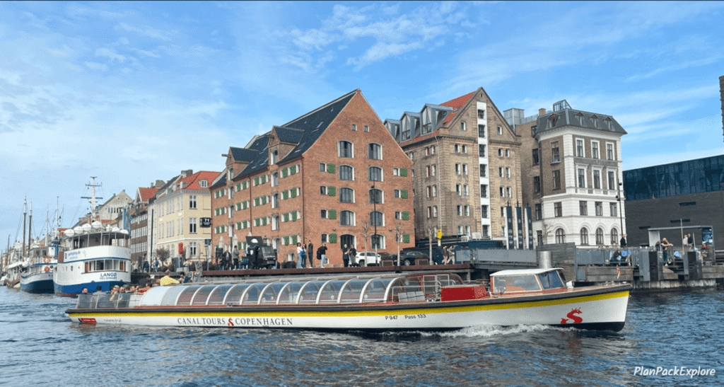 A large tour boat in a canal in Nyhavn, Copenhagen, Denmark.