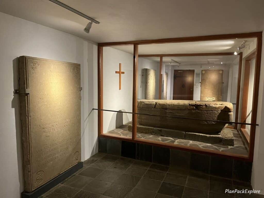 An underground crypt at Skalholt Cathedral in Iceland, with a stone coffin in a glass case.