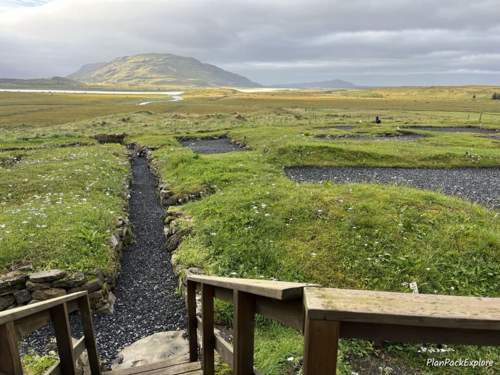 A narrow gravel path leading to an archeological site near Skalholt Cathedral in Iceland, with a mountain view ahead.