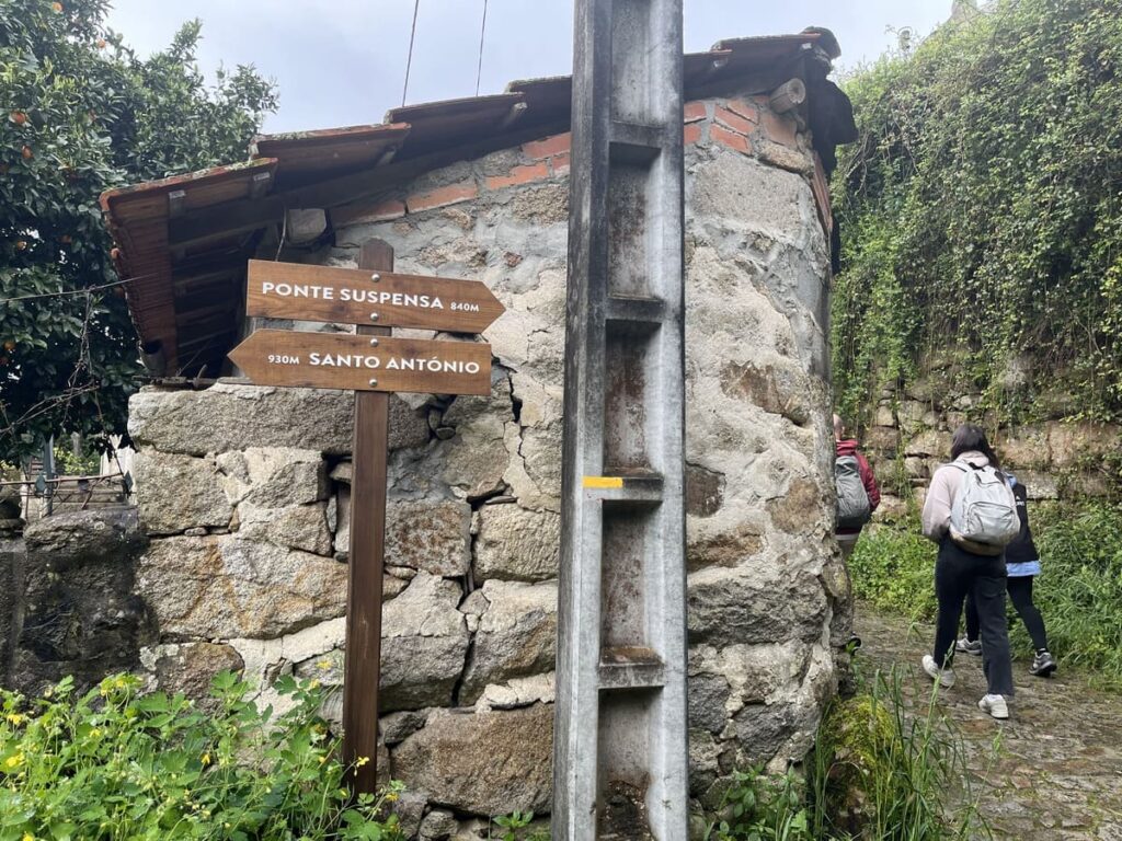 Brown wooden signs near a house, directing travelers to Ponte suspensa, which is the 516 arouca bridge in Portugal.