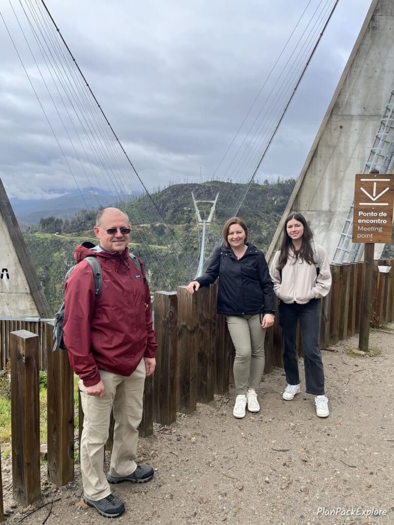3 people standing at the meeting point near the steel suspension bridge called 516 arouca bridge in Portugal.
