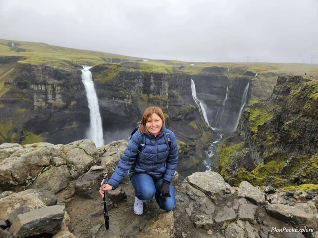 A person in a navy jacket in front of two tall waterfalls in Thjorsardalur Valley, Iceland.