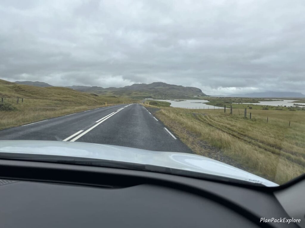 a paved road with a body of water and a mountain in the background on the way to Thjorsardalur Valley, Iceland.