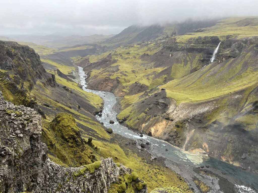 An aerial view of the river and green moss-covered cliffs of Thorsardalur, Iceland