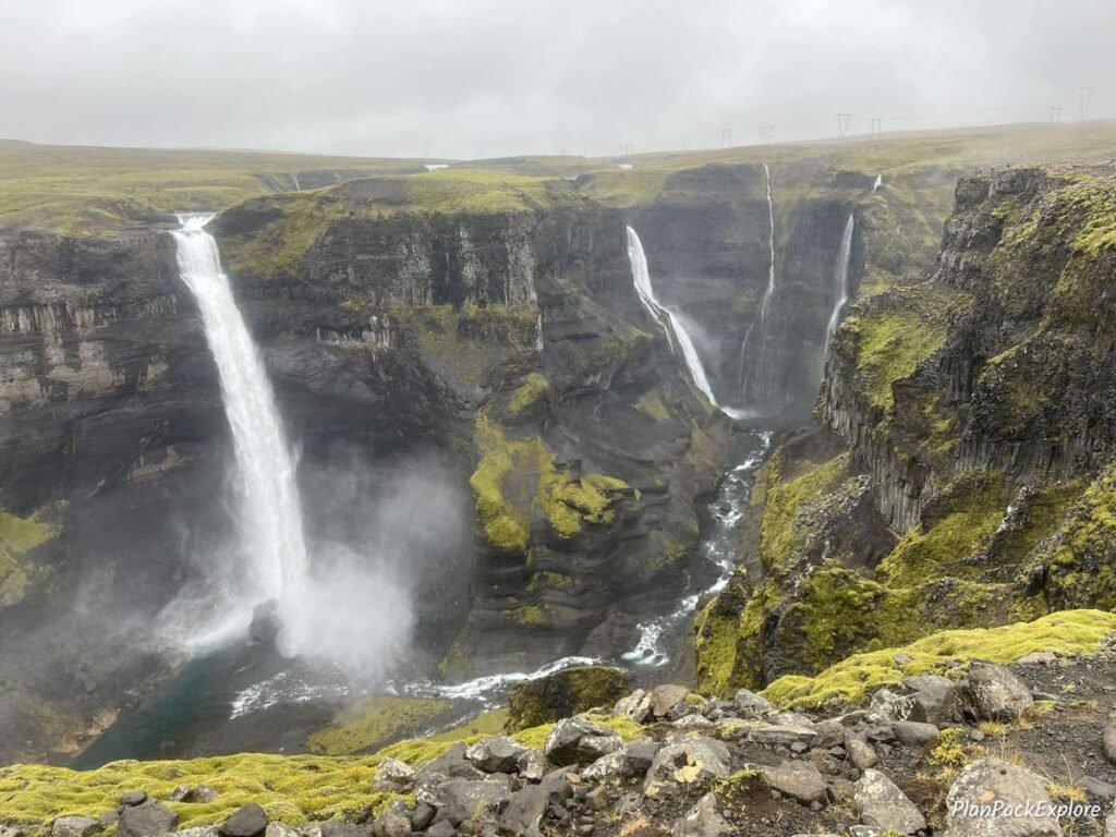 Two waterfalls cascading down a tall cliff in Thjorsardalur Valley, Iceland.