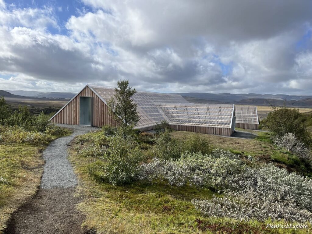 A large wooden structure, shaped like a house, with a clear roof at Sting in Thjorsardalur Valley, Iceland.