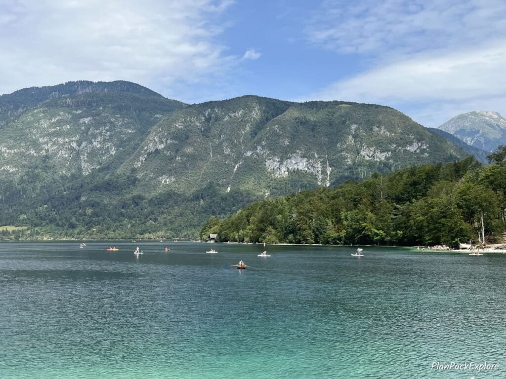 A distant vie of people on SUPS and kayaks on Lake Bohinj in Slovenia.