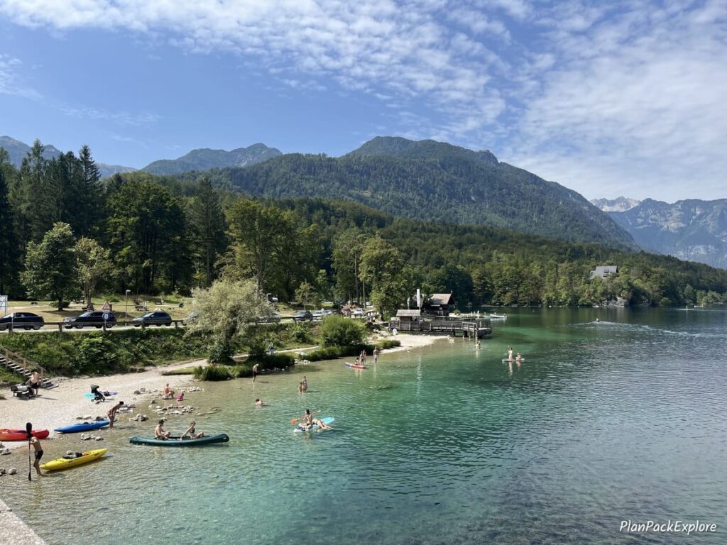 A busy small sandy beach on the shore of lake Bohinj Slovenia.