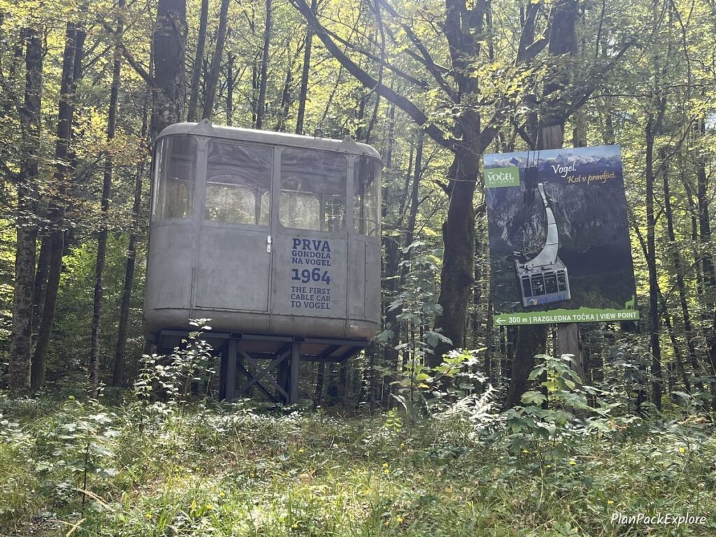 An old original Vogel cable car gondola displayed in a wooded area in Slovenia.
