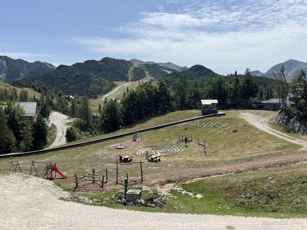 An aerial view of a grassy playground with wood structures at the top of vogel cable car station in Slovenia.