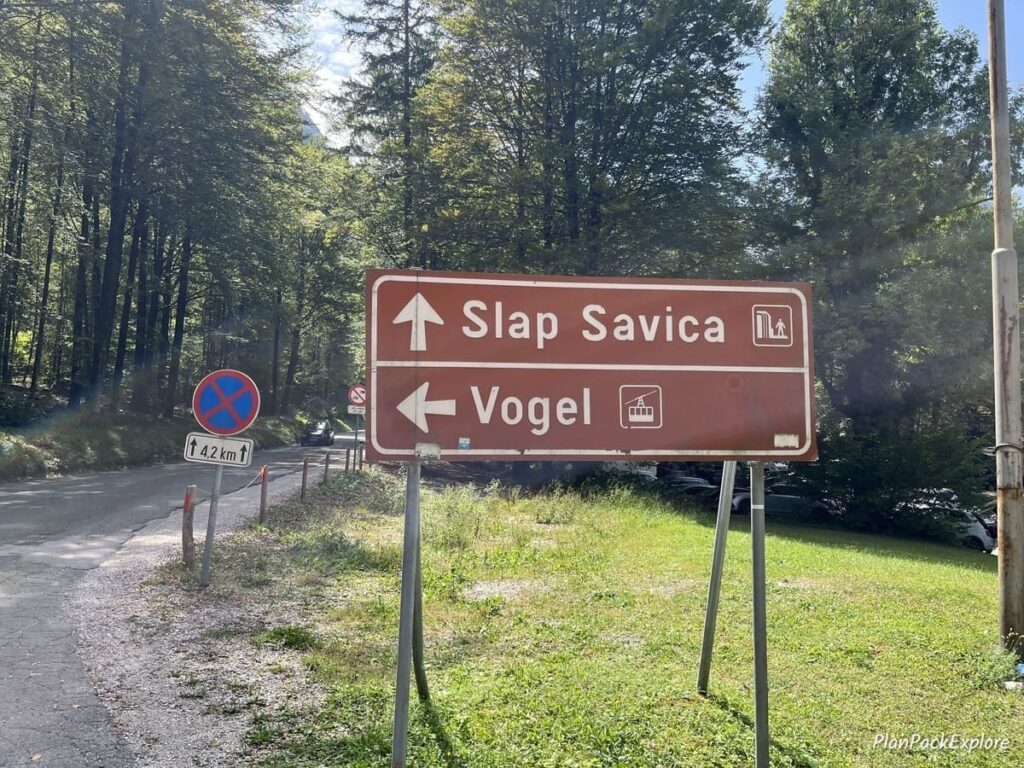 A brown sign with wite letters directing visitors to the Vogel cable car and Savica waterfall near lake bohinj in Slovenia.