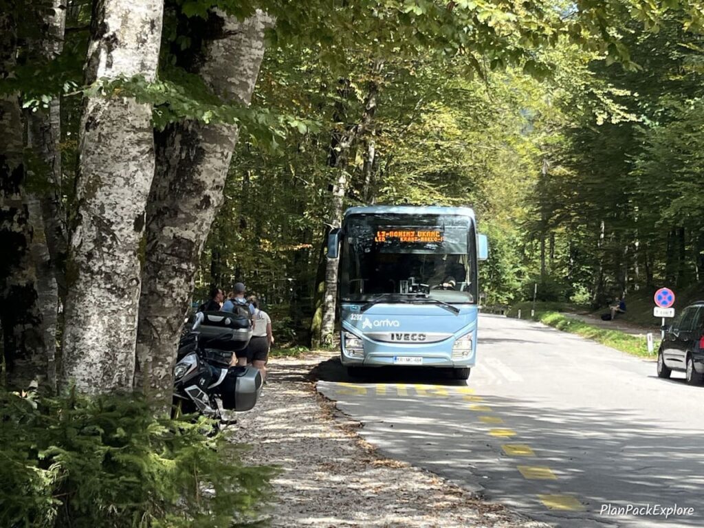 A blue bus on the road in a wooded area by Lake Bohinj in Slovenia.