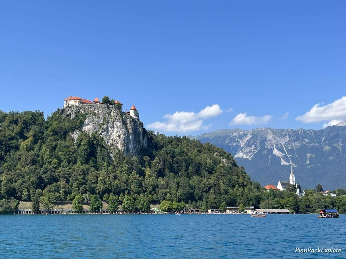 A castle on top of a tall rocky hill by Lake Bled in Slovenia.
