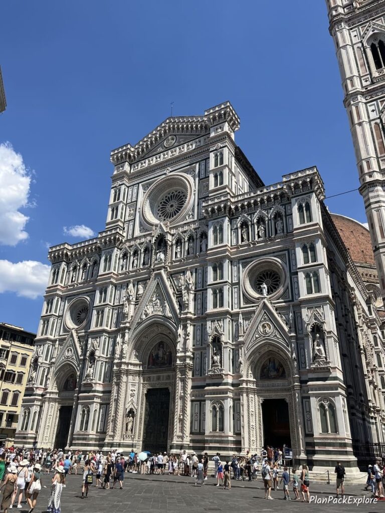 The main entrance to the Florence Cathedral with a line of people in the front.