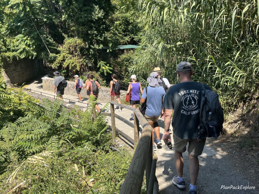People walking on a trail in a wooded area in Cinque Terre, Italy.