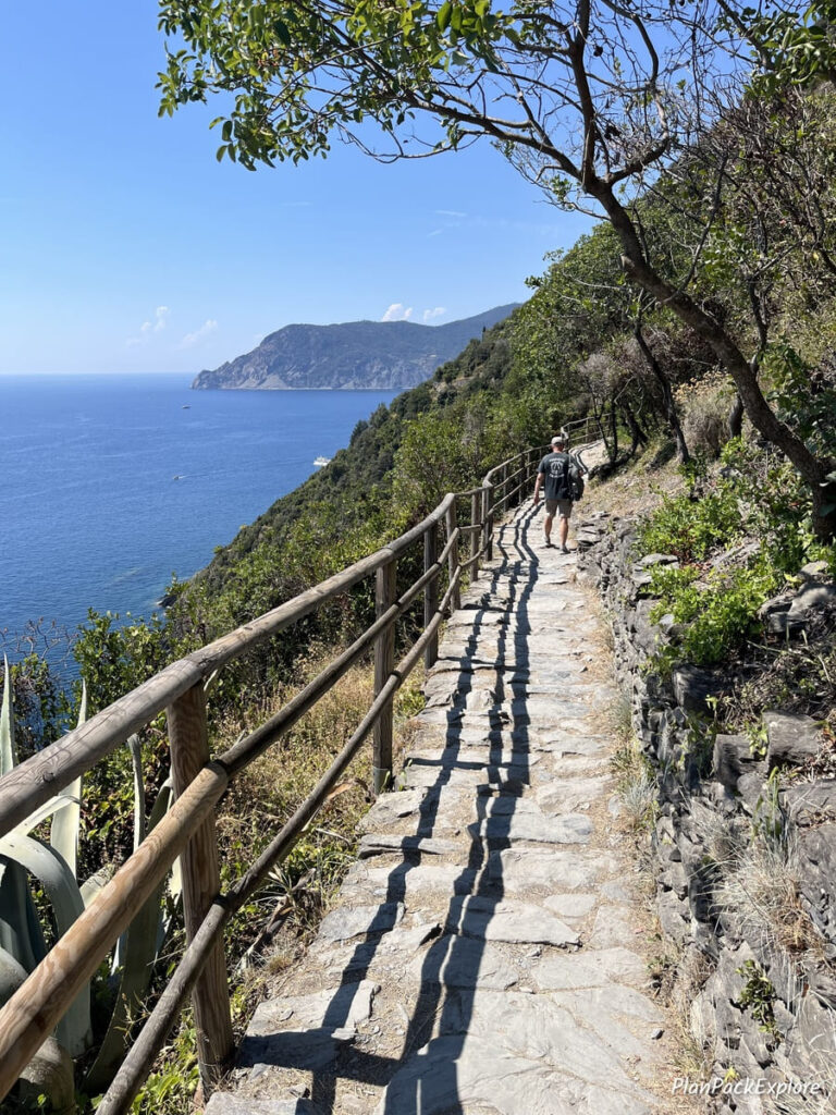 A person walking on a trail near the sea in Cinque Terre, Italy.