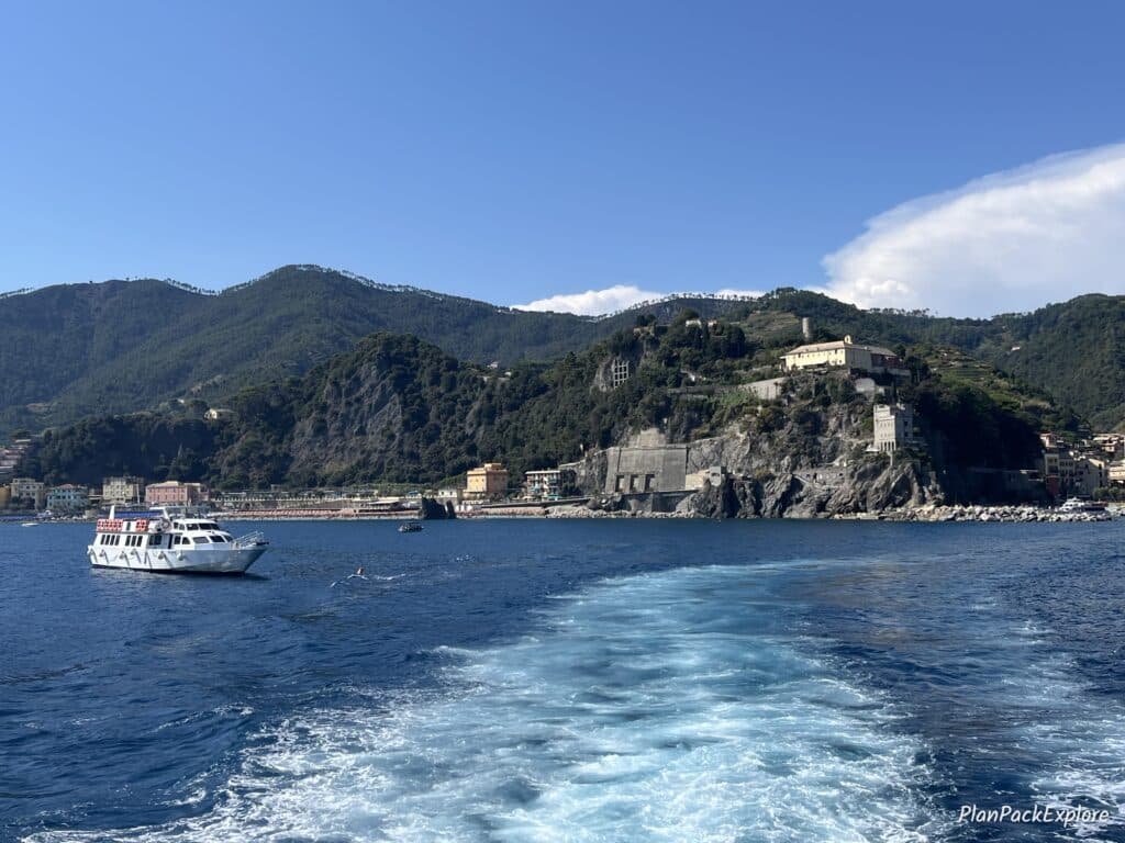 A view of a rocky coast and a distant village in Cinque Terre, Italy, from the ferry ride.