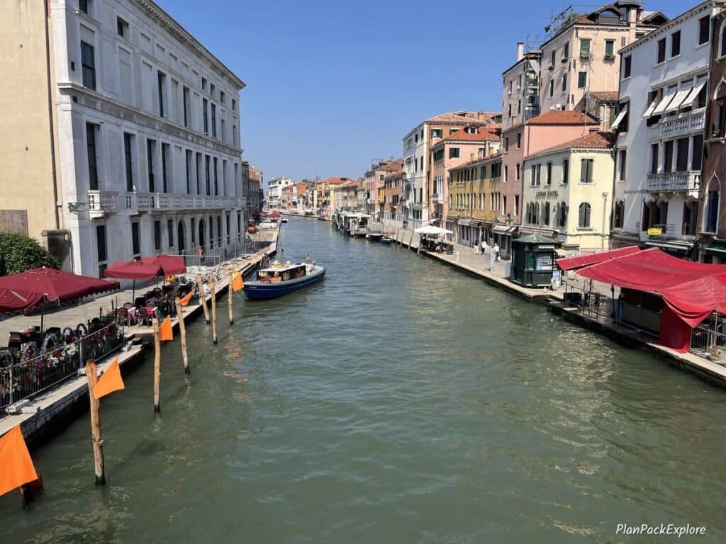 Alleys lined with cafes on both sides of a wide canal in Venice, Italy.