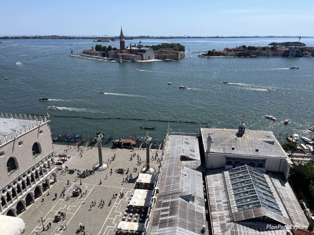 An aerial view of Piazzetta San Marco in Venice with two pink marble columns and the Grand Canal in the background.