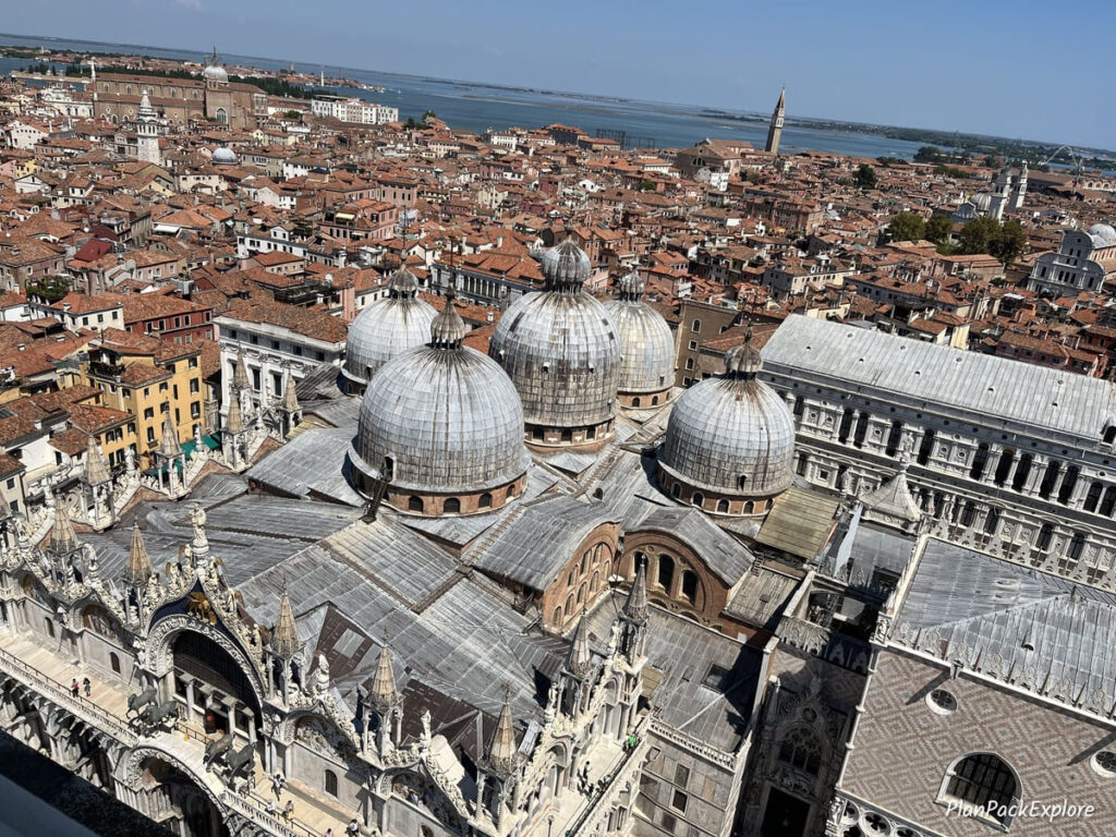 An aerial view of the red rooftops and stone cupolas of St. Mark's Basilica in Venice, Italy.