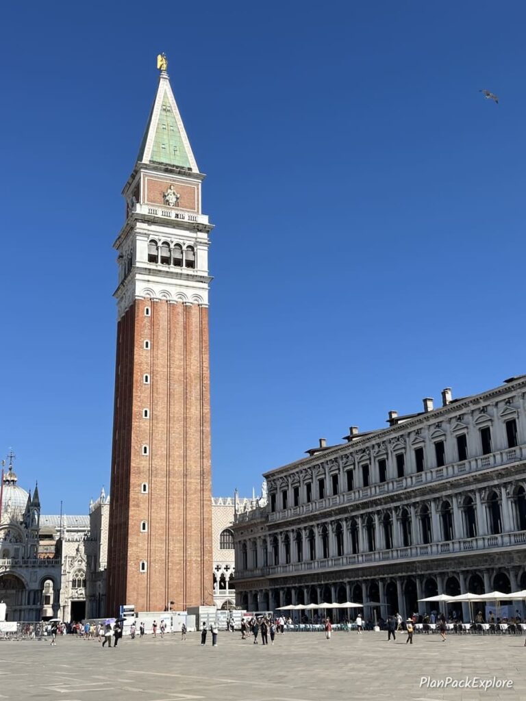 A tall bell tower in the center of a large square, called Piazza San Marco in Venice, Italy