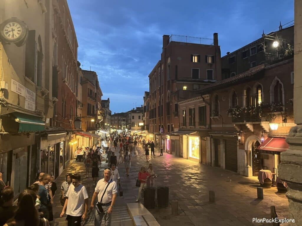 People walking on a street in Venice at night.