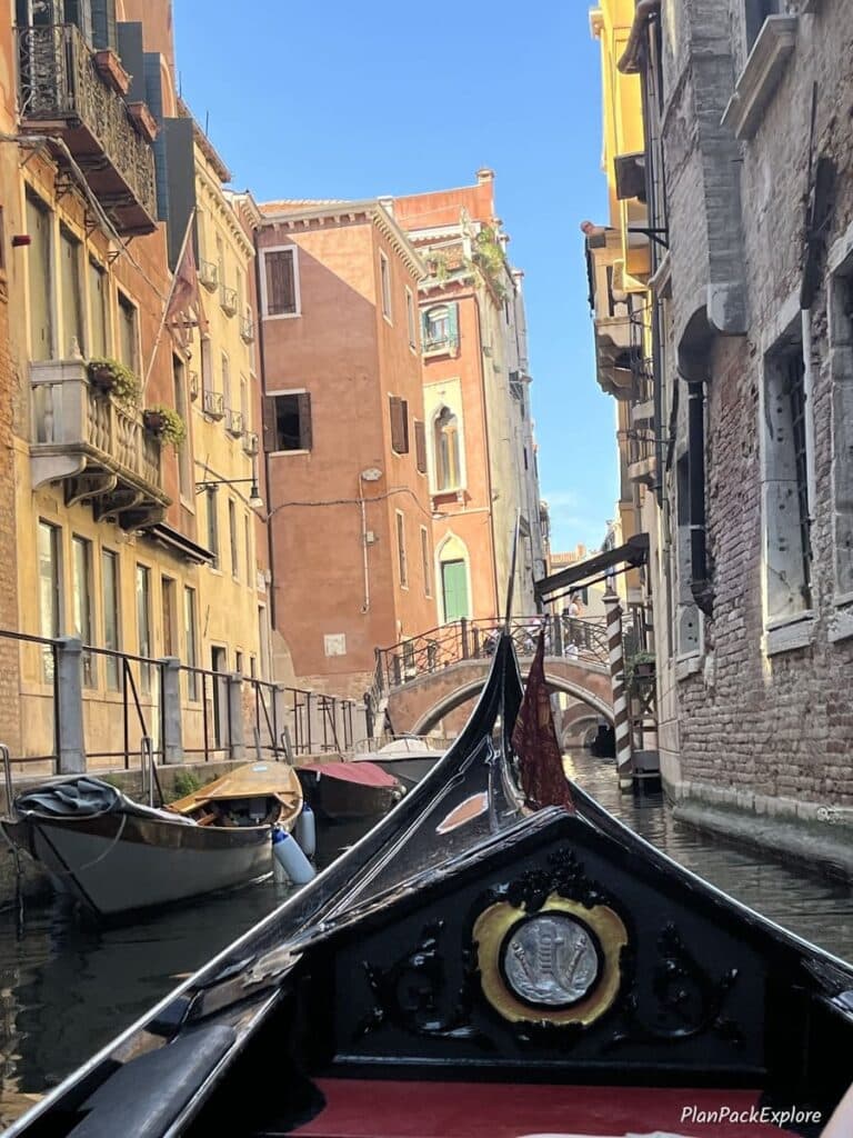A tip of the gondola on a narrow canal between colorful historic buildings in Venice, Italy.