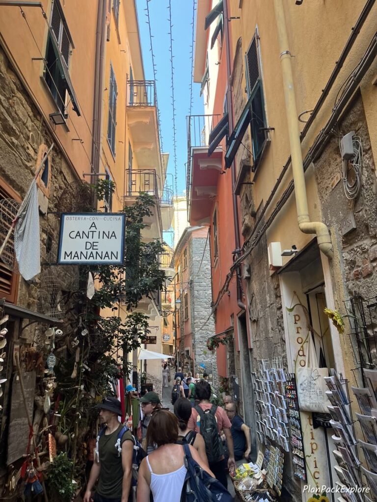People walking through a very narrow street in the village of Corniglia, Cinque Terre, Italy.