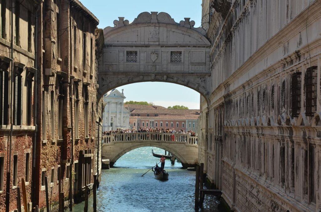 A white marble covered bridge above a canal, called the Bridge of Sighs, in Venice, Italy.