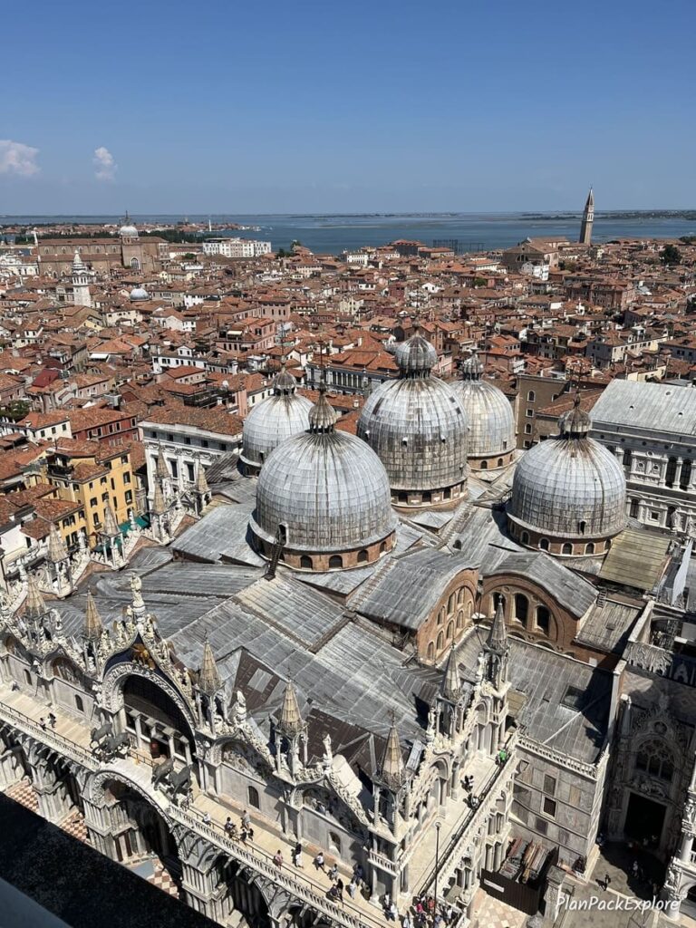 An aerial view of the red rooftops and stone cupolas of St. Mark's Basilica in Venice, Italy.