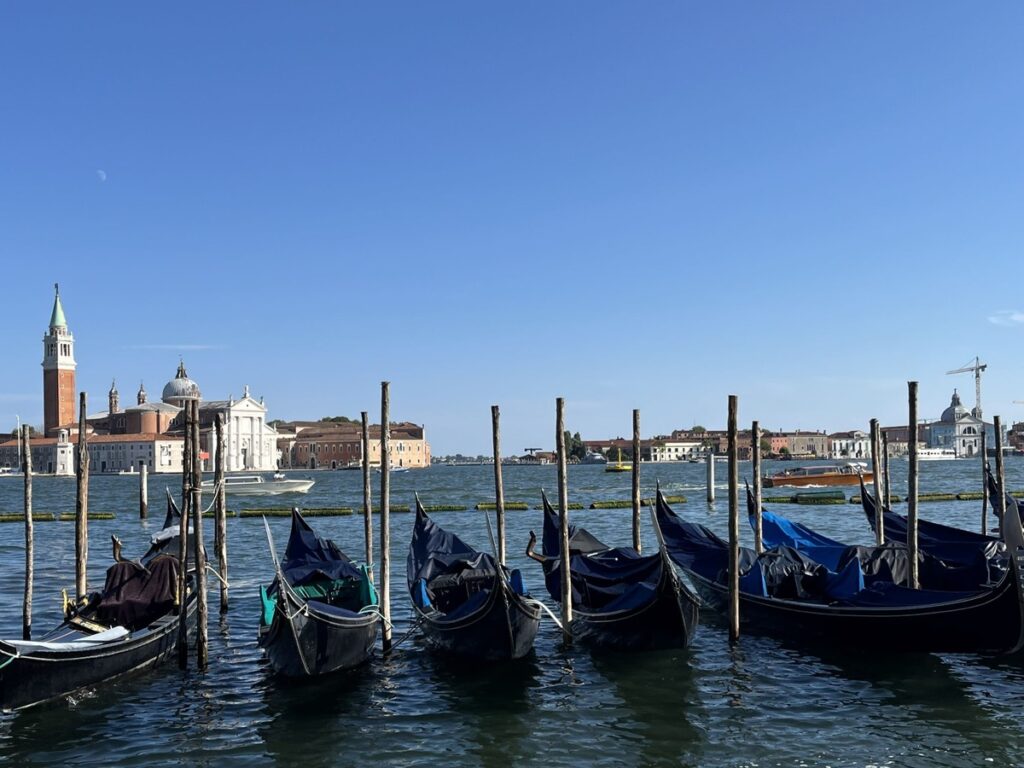 A row of gondolas docked by the pier on the Grand Canal in Venice, Italy.