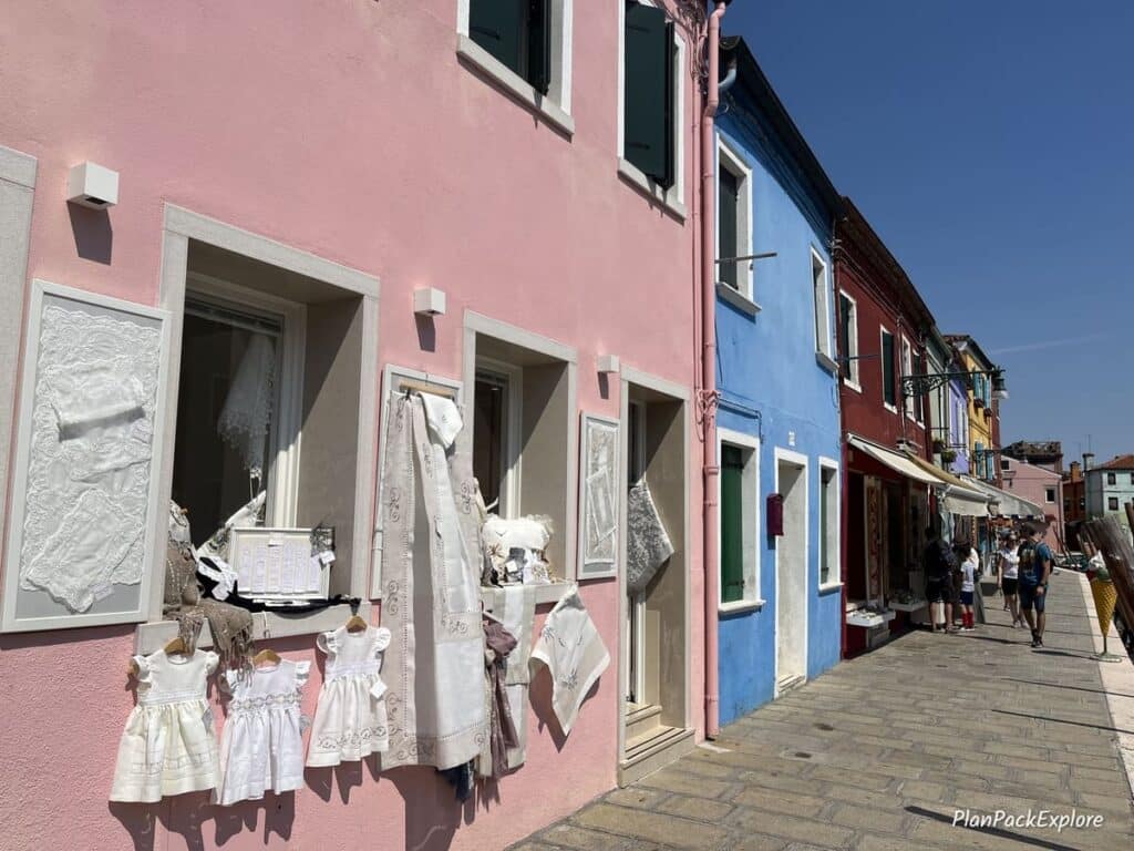 A pink house with a display of lace products in the windows on the island of Burano in Italy.