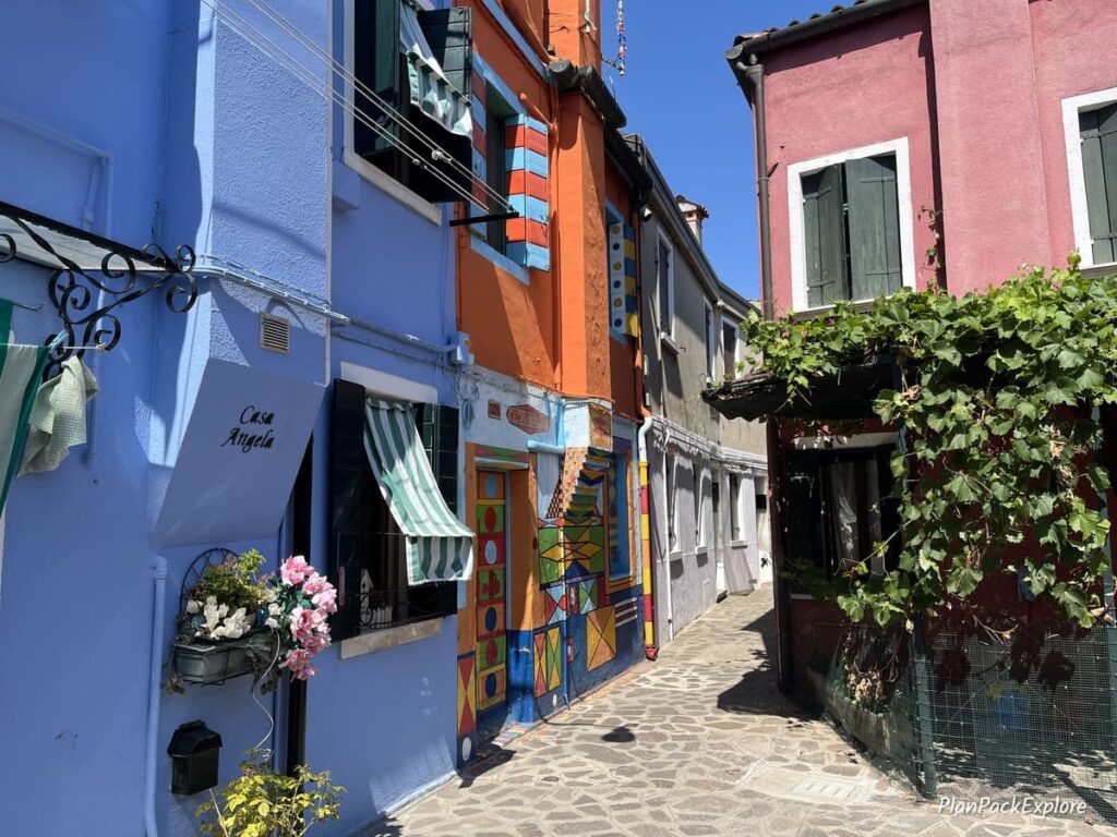 A narrow alley leading to the colorful Casa Bepi house on Burano, Italy.
