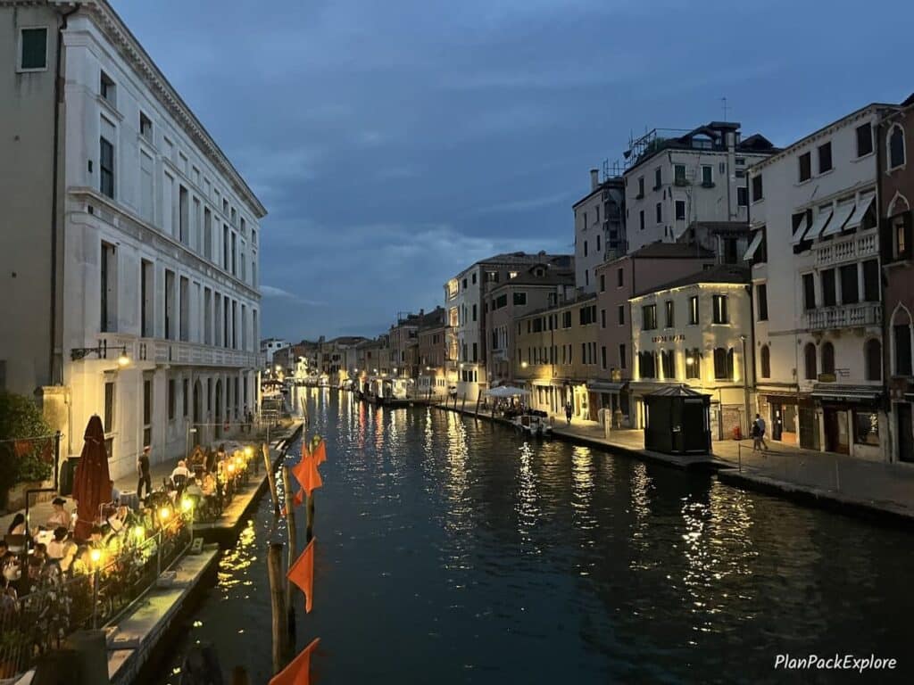 A wide canal in Venice, Italy, illuminated at night.