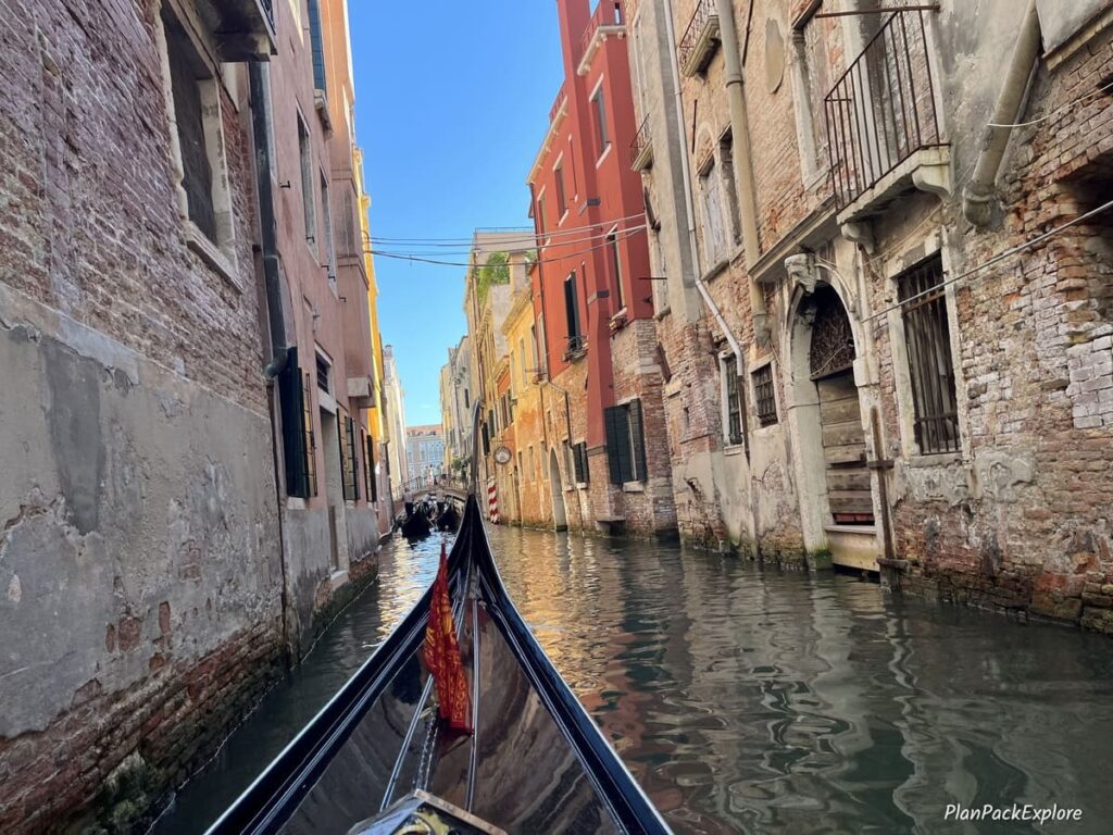 A tip of the gondola on a narrow canal between colorful historic buildings in Venice, Italy.