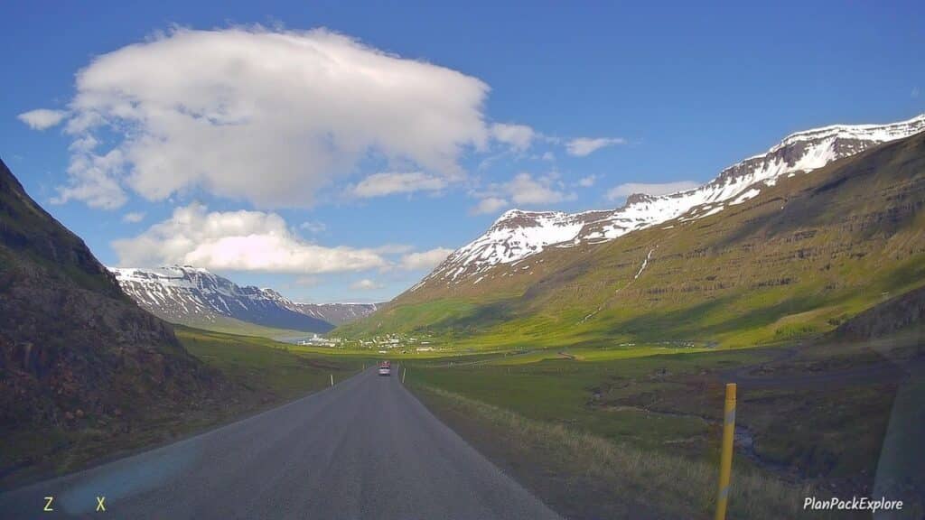 A paved mountain road with snow-capped peaks leading to Seydisfjordur in Iceland.