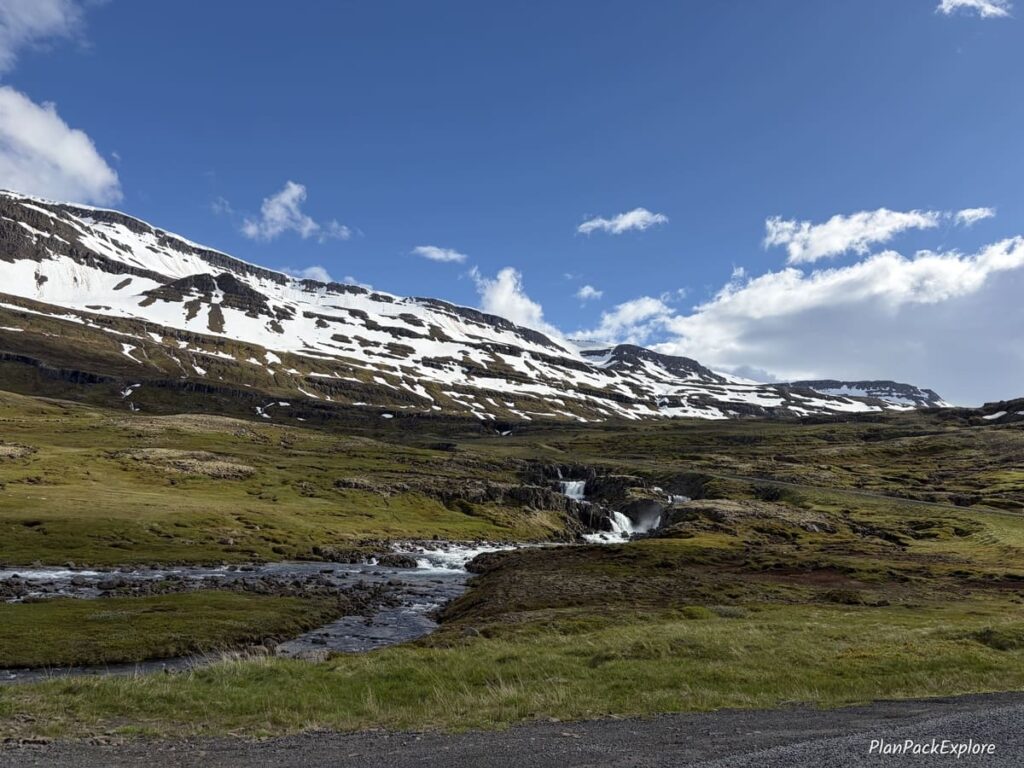 A small waterfall in a grassy area near the mountain pass leading to Seydisfjordur, Iceland.