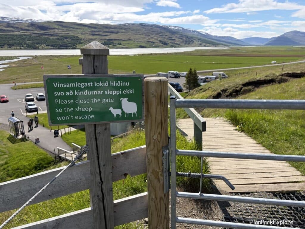A gate with a green sign asking to keep it closed near the trail to Hengifoss Waterfall in Iceland.