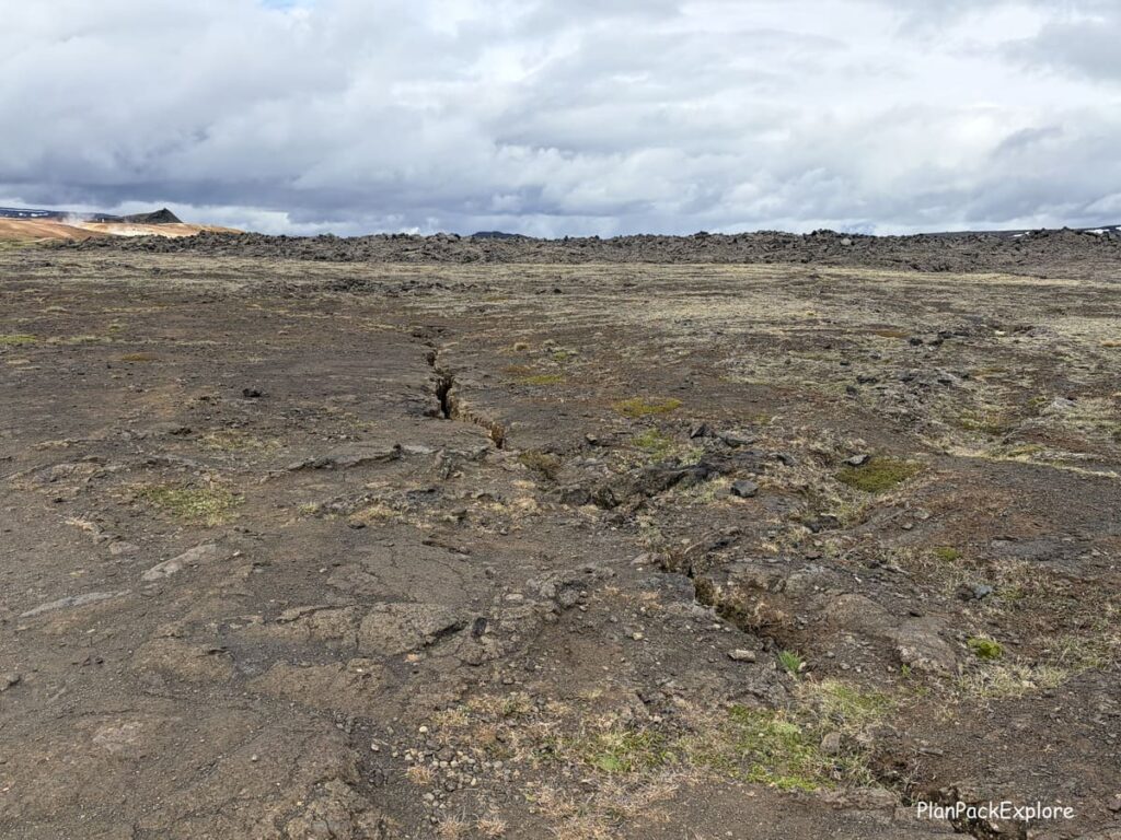 A flat lava field with a long crack in the ground at Leirhnjukur in Iceland.