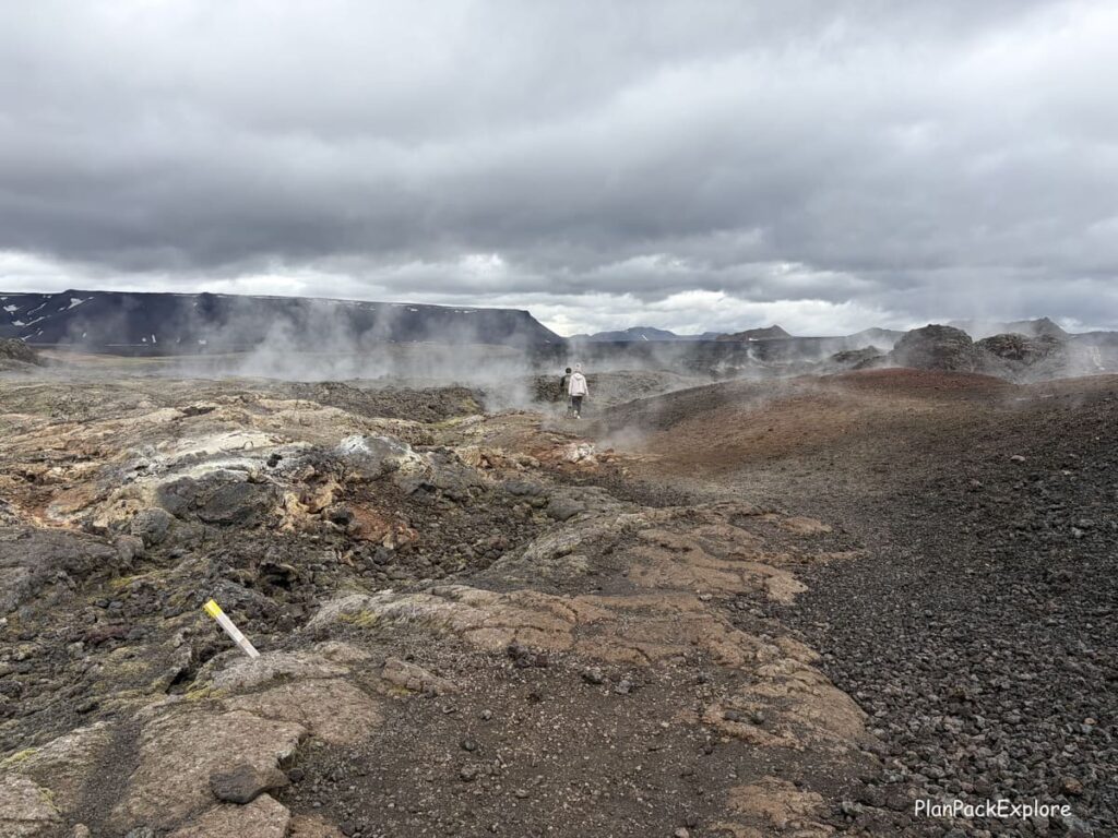 Two people walking on a path through a steaming lava field near Lake Myvatn in Iceland.