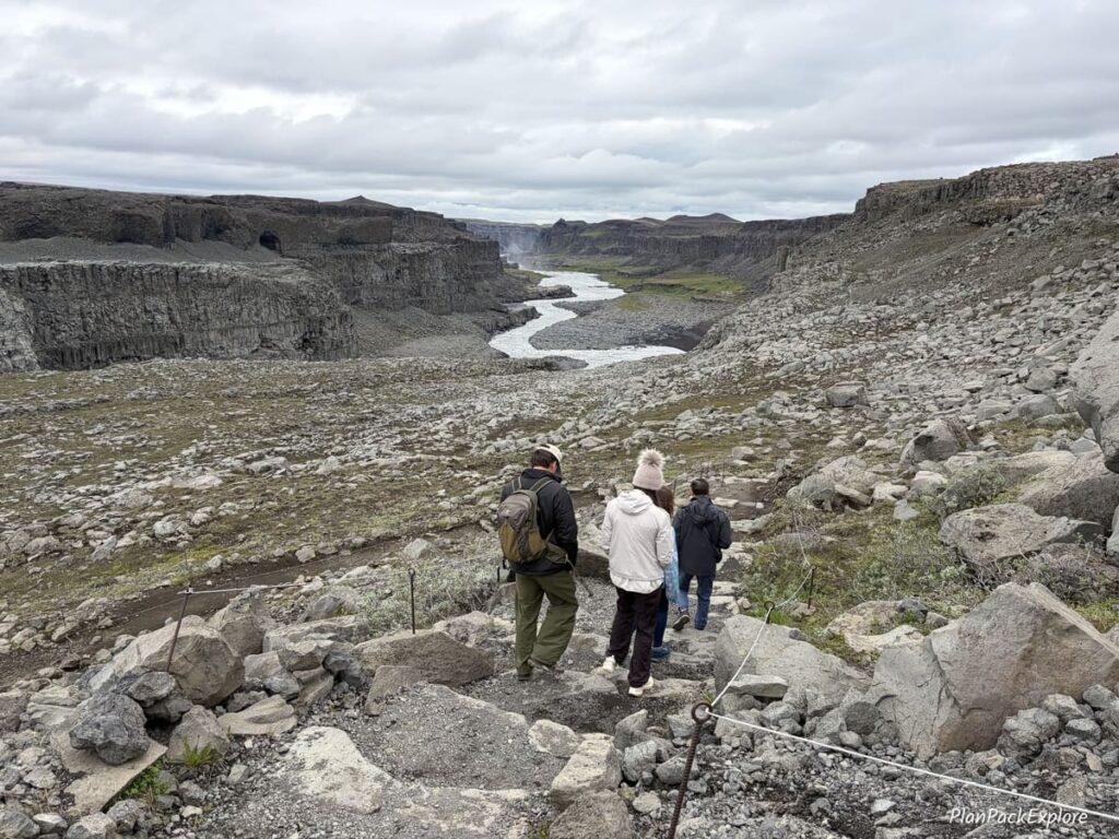 People on the stone stairs leading down to a rocky path for Dettifoss waterfall in Iceland.